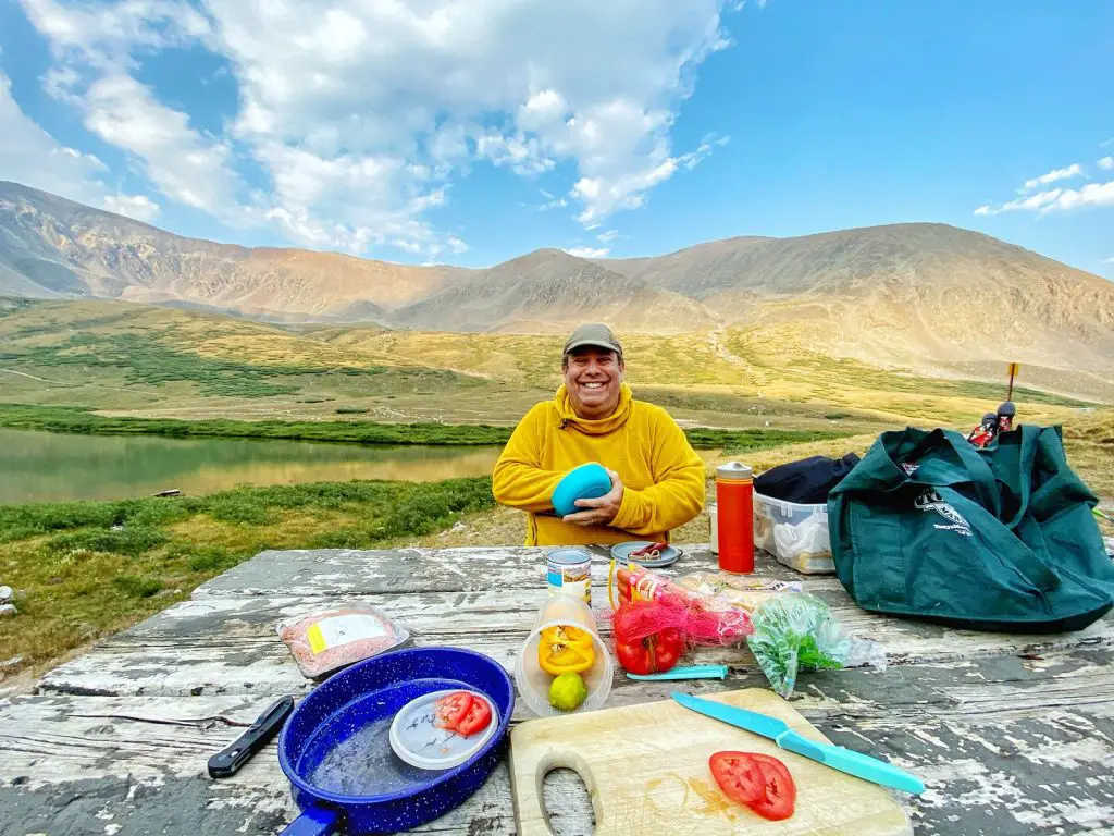 Mann im gelben T-Shirt mit Rundhalsausschnitt, der tagsüber auf dem Boden in der Nähe des Berges sitzt