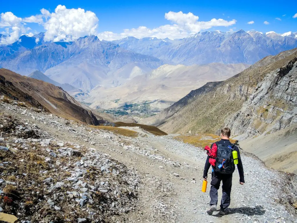 man carrying backpack walking on mountain at daytime