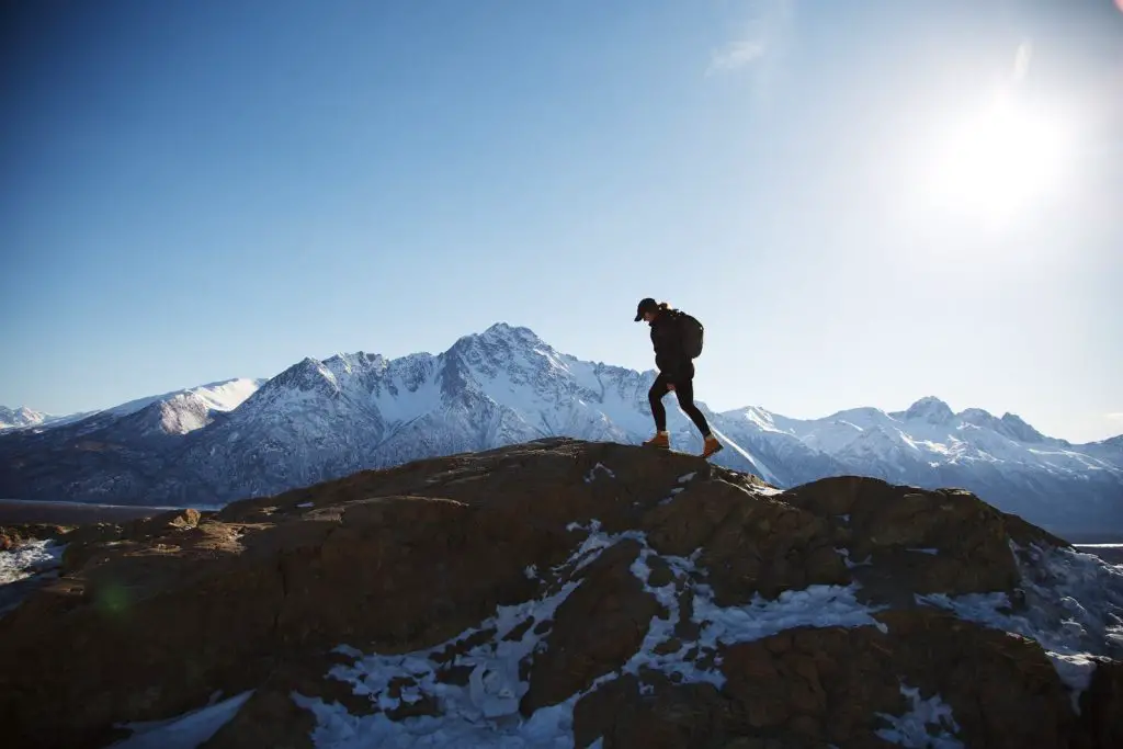 Mann in schwarzer Jacke, der tagsüber auf einem felsigen Berg steht