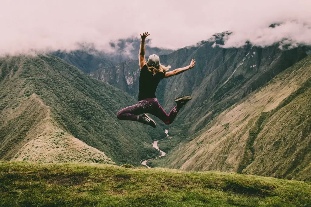 Frau springt auf grüne Berge
