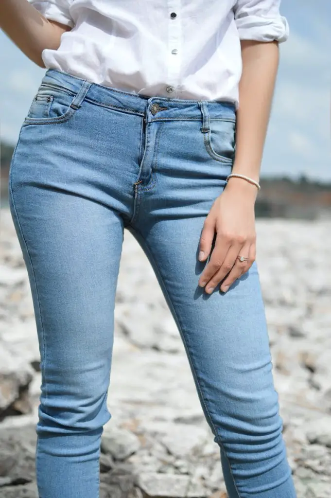 stehende Frau in Jeans und weißem Oberteil